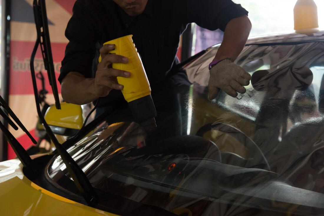 worker applying tint in the windshield